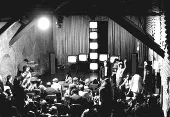 Installation view of an artwork comprising performers and television screens