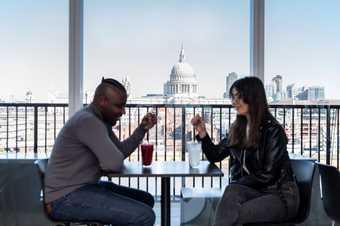 Two people sit in the members bar drinking with the backdrop of st pauls in the background